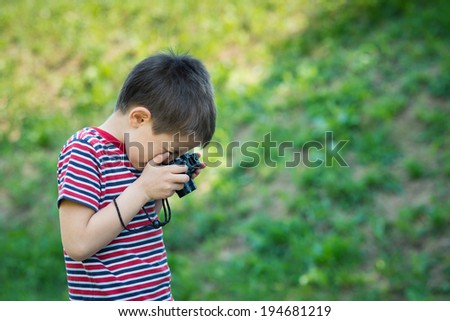 Portrait of child with digital compact camera outdoors.