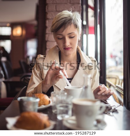 Young woman drinking coffee in a cafe in Paris, France. Shallow depth of field.