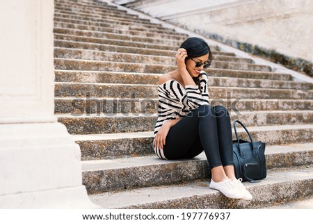 Young beautiful brunette woman portrait outdoors sit on stairs.