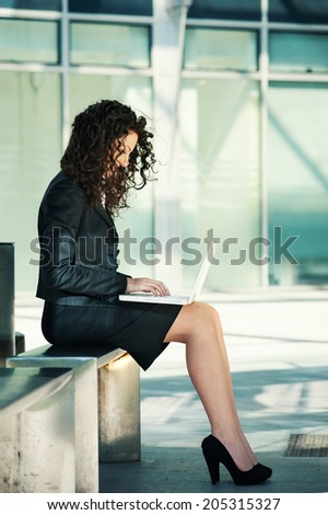 Business woman outdoors using laptop. Full body portrait.