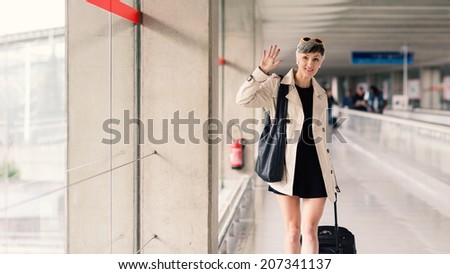 Businesswoman greeting with hand at Charles de Gaulle airport, Paris.