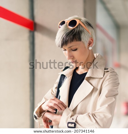Businesswoman looking at watch at Charles de Gaulle airport, Paris.