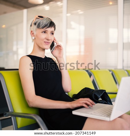 Businesswoman working with portable computer while talking at the phone at Charles de Gaulle airport, Paris.