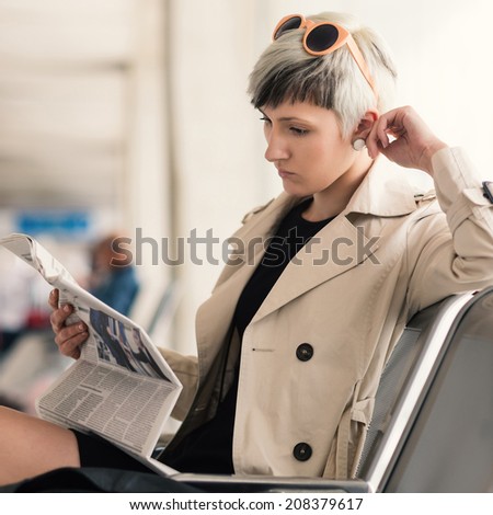 Businesswoman reading newspaper at Charles de Gaulle airport, Paris.