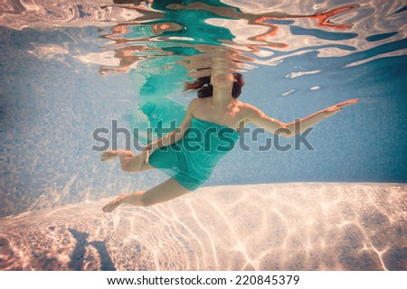 Underwater woman portrait wearing green dress in swimming pool. Filtered image.