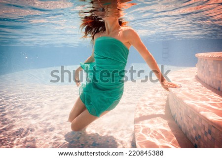 Underwater woman portrait wearing green dress in swimming pool. Filtered image.