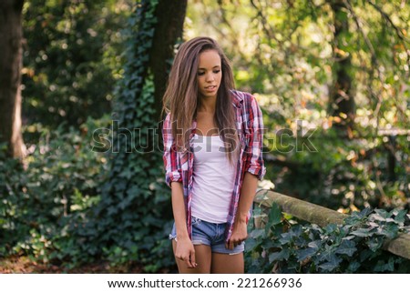 Pretty teenager portrait with natural green hedge background in a park.