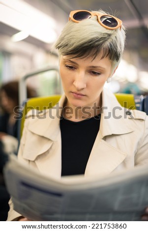 Young woman reading newspaper inside metro subway. Paris, France.