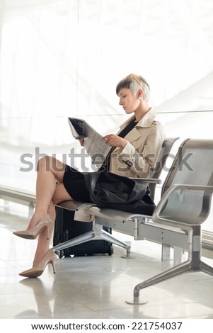Businesswoman reading newspaper at Charles de Gaulle airport, Paris.