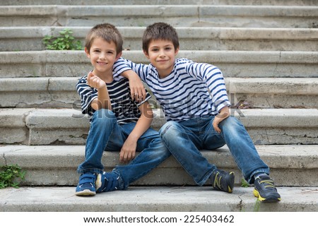 Two brothers portrait having fun sit on stairs outdoors.