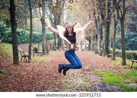 Jumping young woman outdoors in a park in autumn.