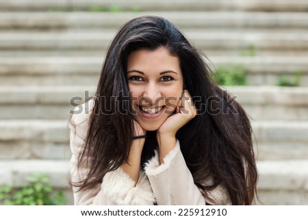 Smiling young woman portrait outdoors sit on stairs in autumn.
