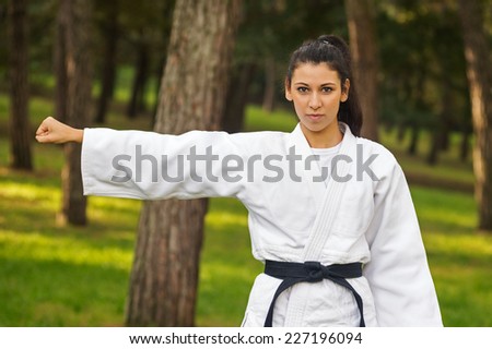 Young caucasian woman practicing judo outdoors in a park.