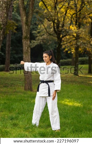 Young caucasian woman practicing judo outdoors in a park.