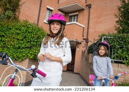 Couple of young girls portrait wearing helmet with bike outdoors.