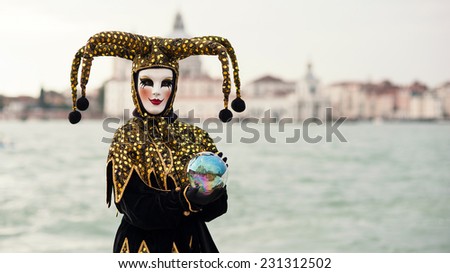 VENICE, ITALY - MARCH 3, 2014: Carnival of Venice, beautiful mask at St. George island with Mark\'s Square in the background.