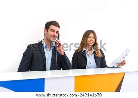 Young man and woman at work as receptionist in hospital talking on the phone for appointment.