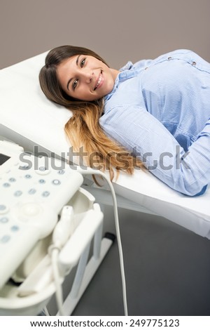 Female patient laying besides ultrasound machine in medical center.