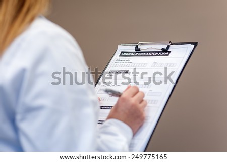 Female doctor compiling medical information form in medical center.