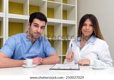 Young couple of doctor and nurse having a break and relaxing with a cup of coffee in medical center.