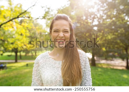 Smiling young woman close up portrait with natural green background in a park. Filtered image with back light effect.
