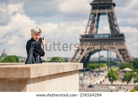 Happy young woman with camera in front of the Eiffel Tower. Paris, France.
