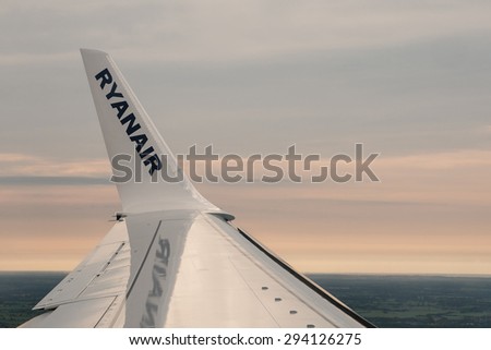 LONDON, UNITED KINGDOM - JUNE 2015: Ryanair logo on the plane wing at sunrise over the European sky. Ryanair is the biggest low-cost airline company in the world.
