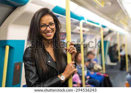 Smiling young mixed race businesswoman portrait inside underground wagon in London.