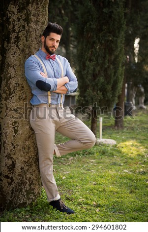 Hipster young man portrait relaxing outdoors in a park. Full body portrait.