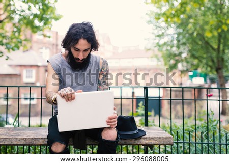 Young tattooed man portrait using laptop in Shoreditch borough. London, UK. Hipster style