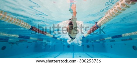 Professional man swimmer inside swimming pool. Underwater panoramic image.