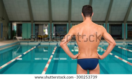 Professional man swimmer inside swimming pool. View from behind.
