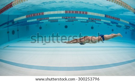 Professional man swimmer inside swimming pool. Underwater image.