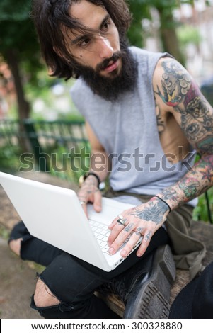 Young tattooed man portrait using laptop in Shoreditch borough. London, UK. Hipster style.