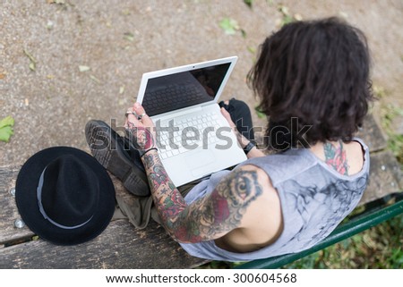 Young tattooed man portrait using laptop in Shoreditch borough. London, UK. Hipster style.