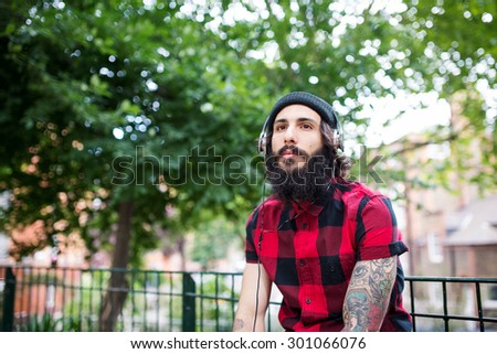Young tattooed man portrait relaxing in a park in Shoreditch borough. London, UK. Hipster style.