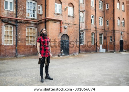 Full body portrait of young tattooed man standing in Shoreditch borough. London, UK. Hipster style.