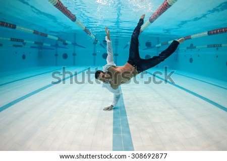 Man portrait wearing white shirt inside swimming pool upside down. Underwater image.