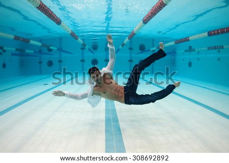 Man portrait wearing white shirt inside swimming pool. Underwater image.