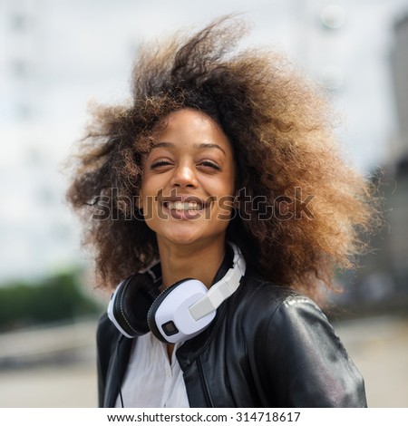Smiling young woman portrait outdoors on Westminster Bridge in London with headphones.