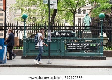 NEW YORK - MAY 12, 2015: People walking on the street in front of Wall St. Subway. The NYC Subway is one of the oldest and most extensive public transportation systems in the world with 468 stations.