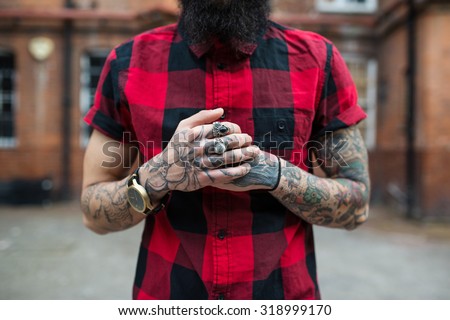 Hands close up of young tattooed man portrait in Shoreditch borough, London. Hipster style.