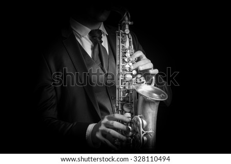 Detail of Saxophone and man hands isolated against black background. Close up studio portrait, black and white image.