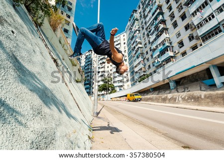 Full body portrait of parkour man jumping high in the street.