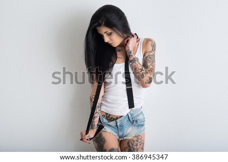 Woman portrait with tattoo against white wall background.