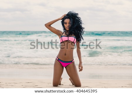 Beautiful young woman full body portrait wearing bikini relaxing on South Beach. Miami, florida.