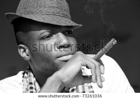 Black man smoking cigar portrait with hat. Black and white photo.