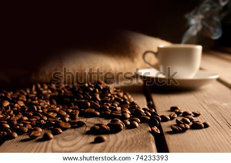 Coffee background with beans and white cup. Dark atmosphere and copy space.