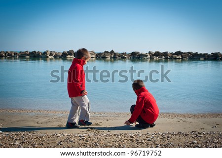 Two brothers playing on the beach in a sunny day.