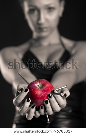 Conceptual image of beautiful girl with nails driven apple. Shallow depth of field.
